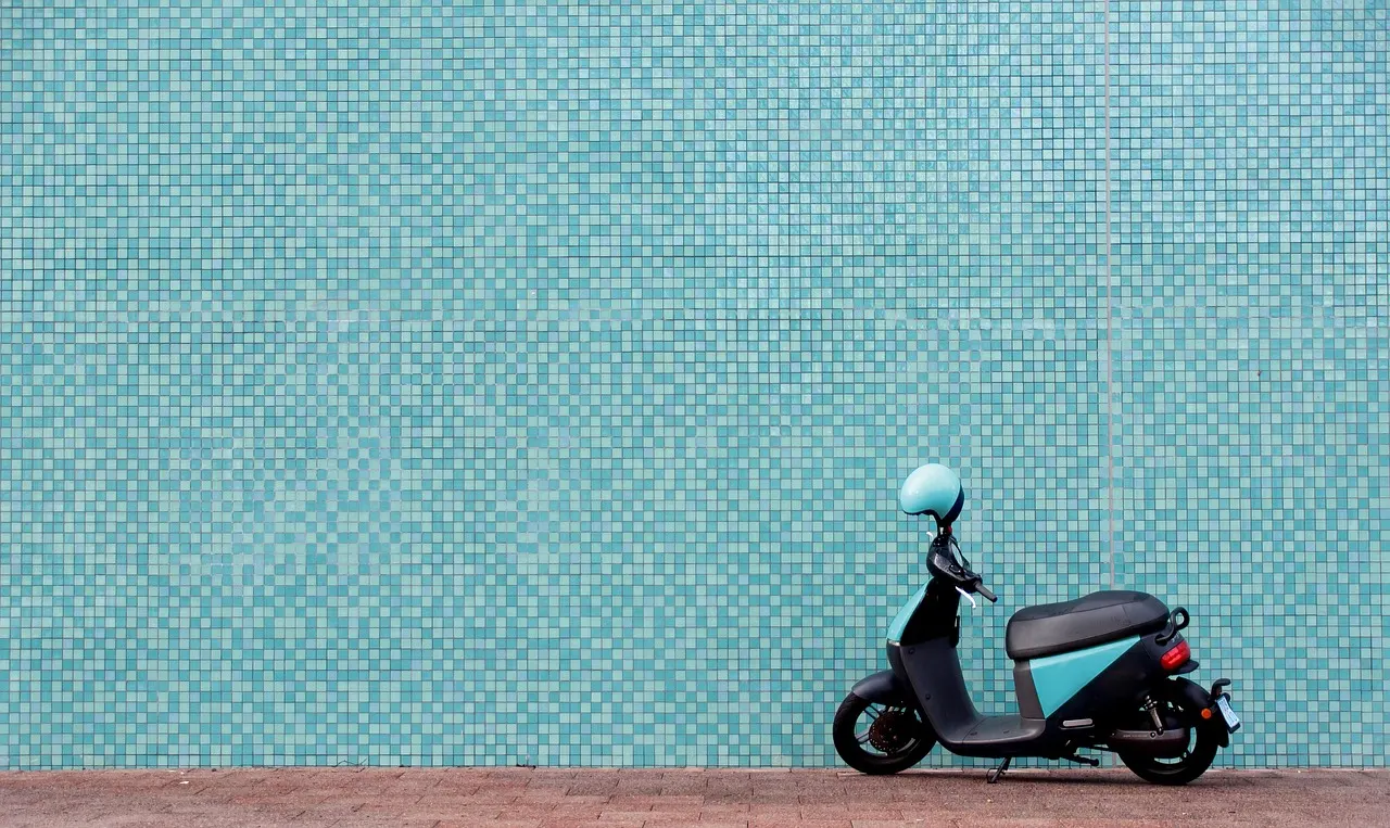 Scooter électrique garé devant un mur de mosaïque turquoise