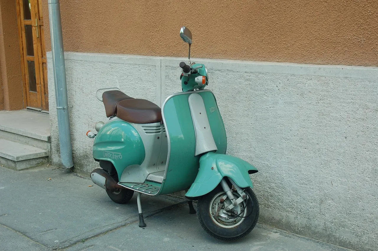 Scooter vert garé contre un mur, au pied d’une maison